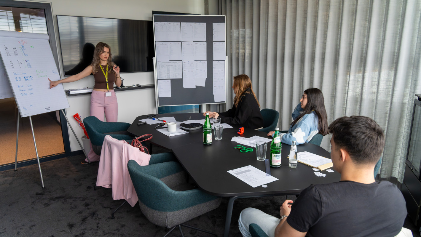 Vier Teilnehmende in der Beratung; ein Mädchen steht am Flipchart