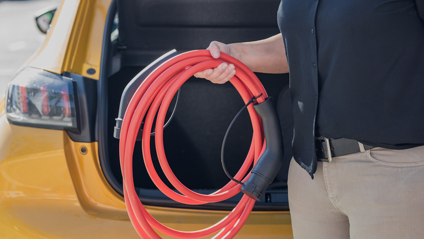 Person mit einem Ladekabel für ein Elektroauto